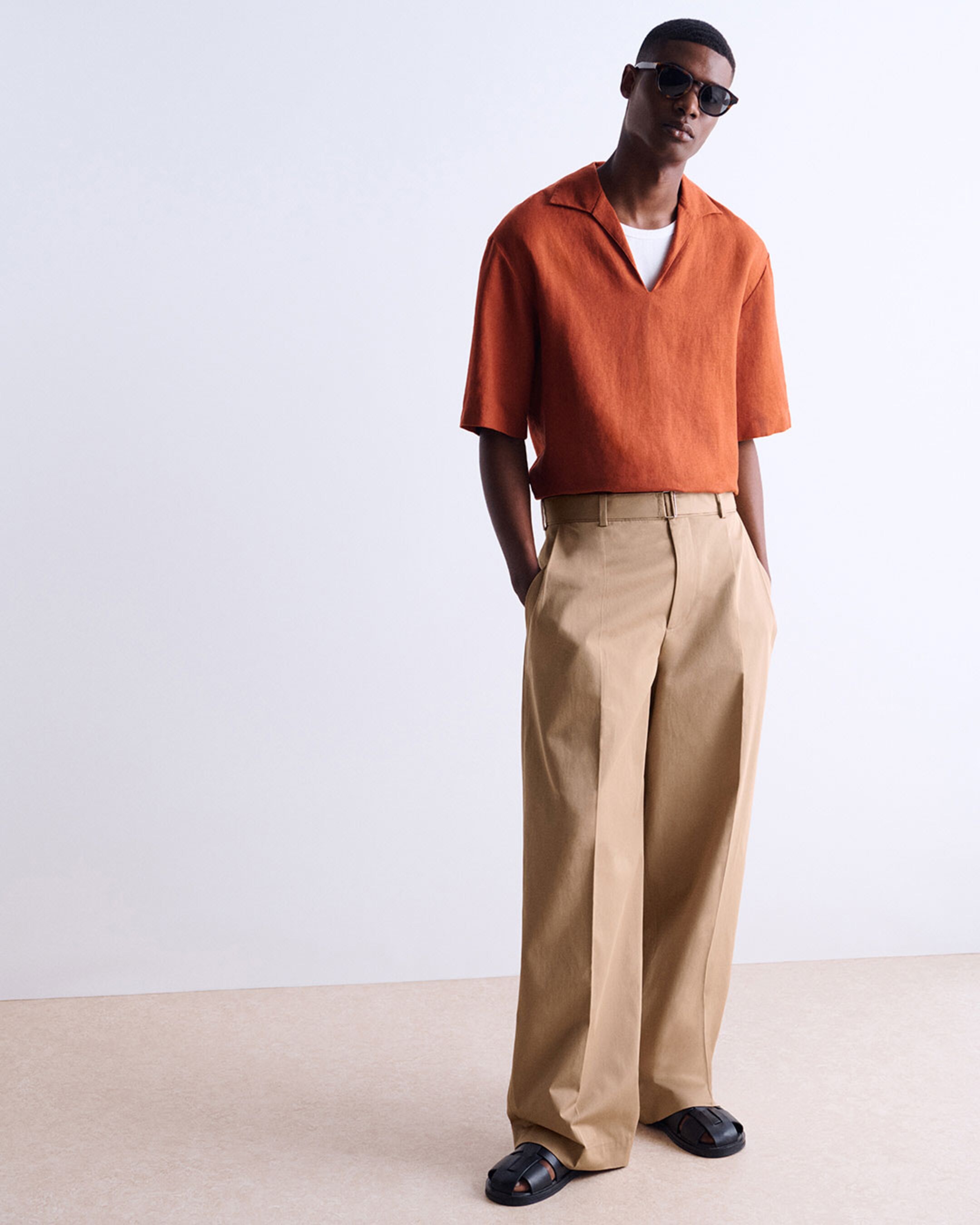 man in orange top and camel pants