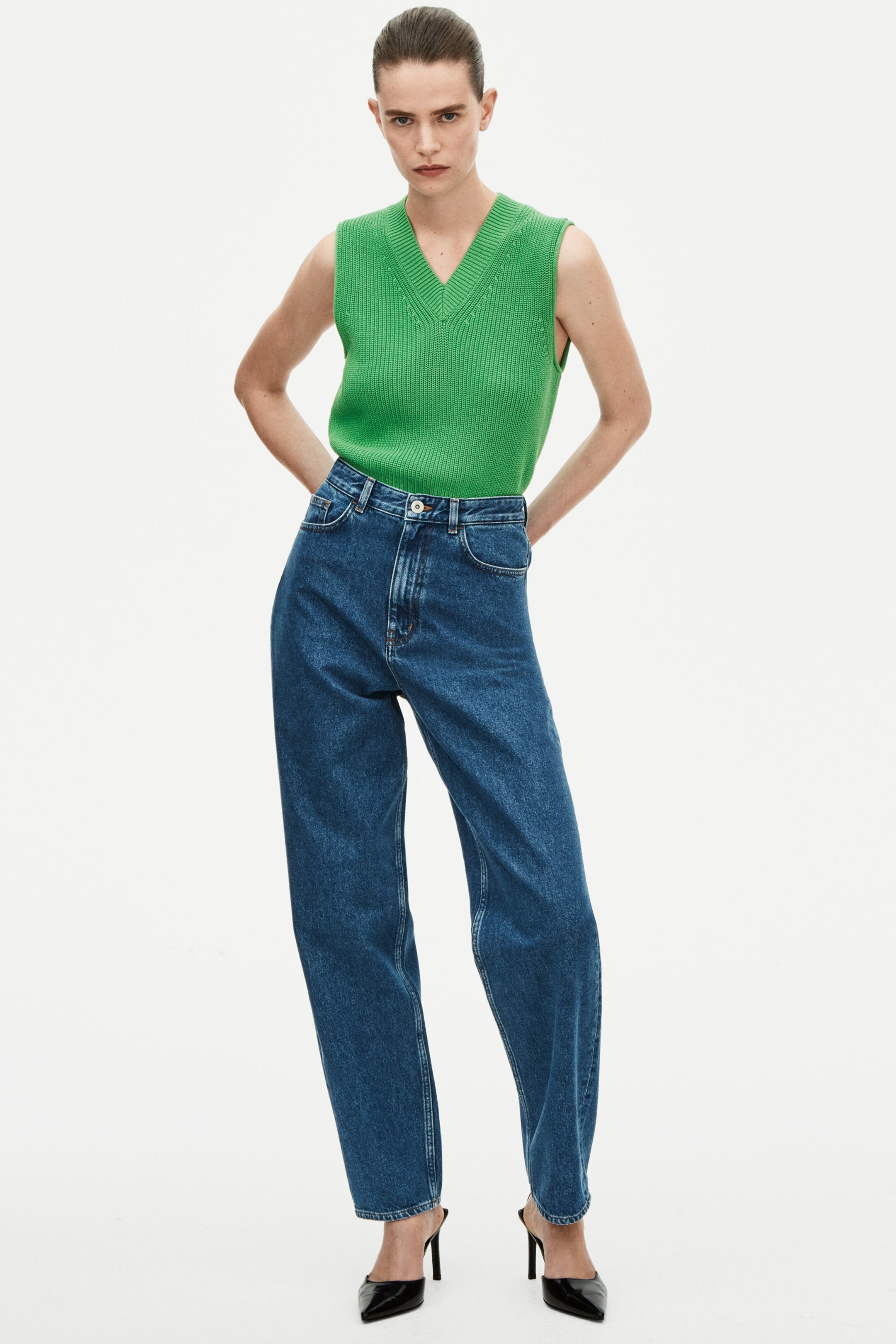 Woman wearing green knitted vest and blue jeans