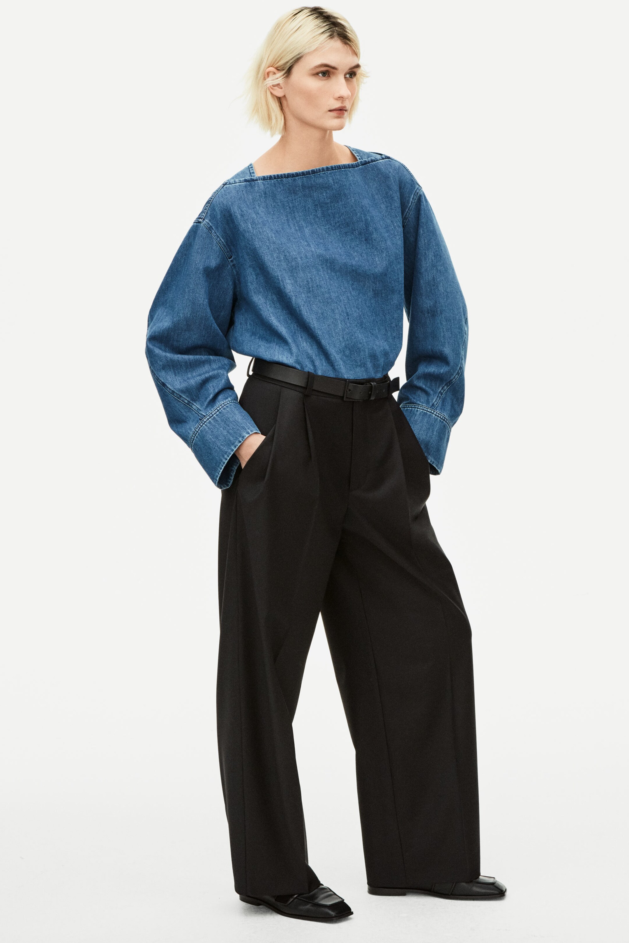 Woman wearing blue demin long sleeved top and black tailored trousers