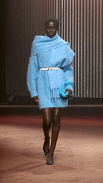 Placeholder for: Woman wears blue knitted dress, blue scarf and carries blue bag