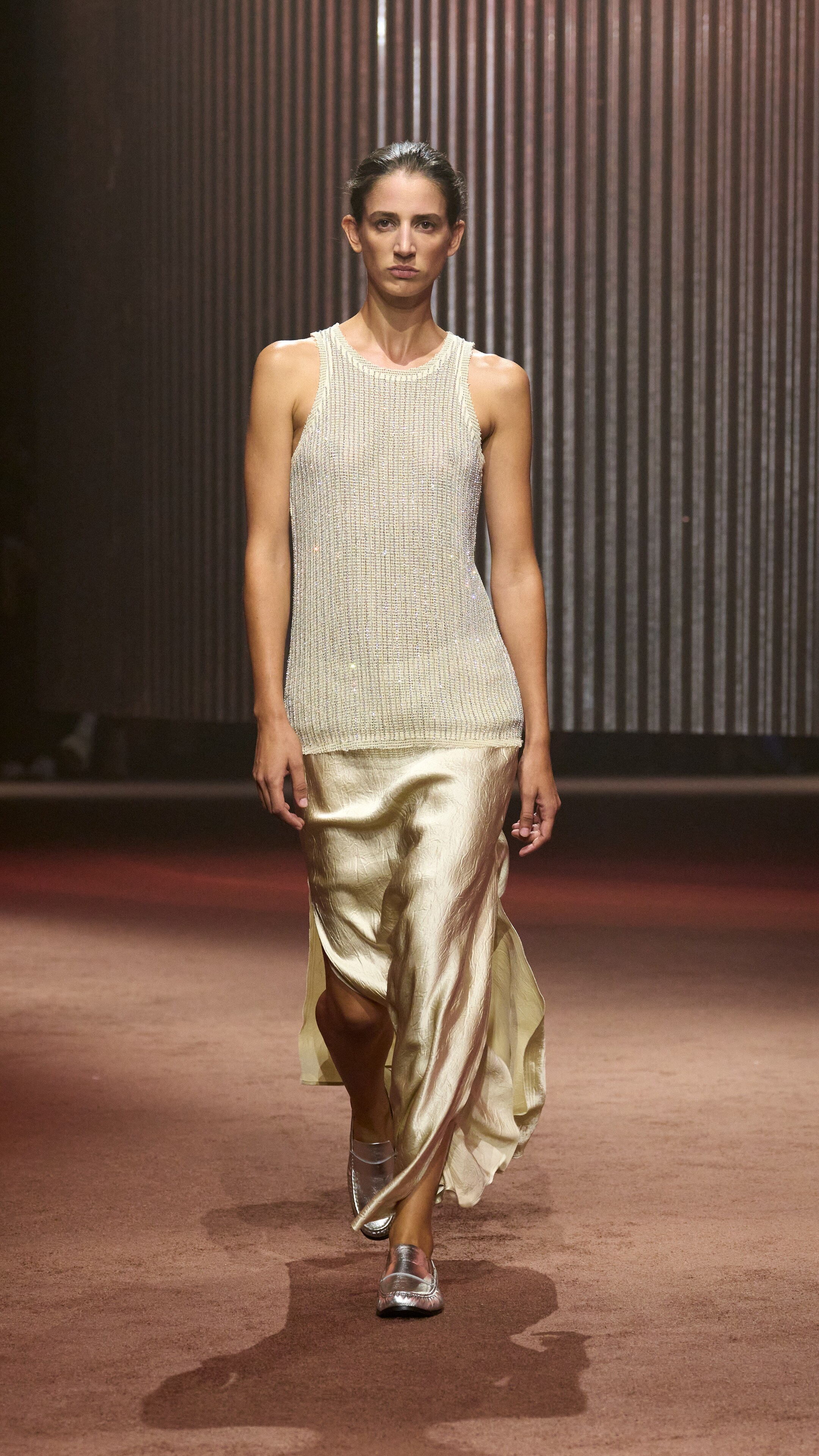 Woman wears beige knit vest and light gold skirt