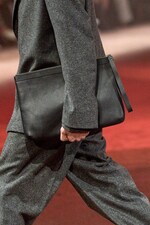 Placeholder for: Model wears grey coat, grey pants and holds black leather bag