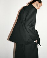 Placeholder for: Backshot of woman in black suit with large earrings