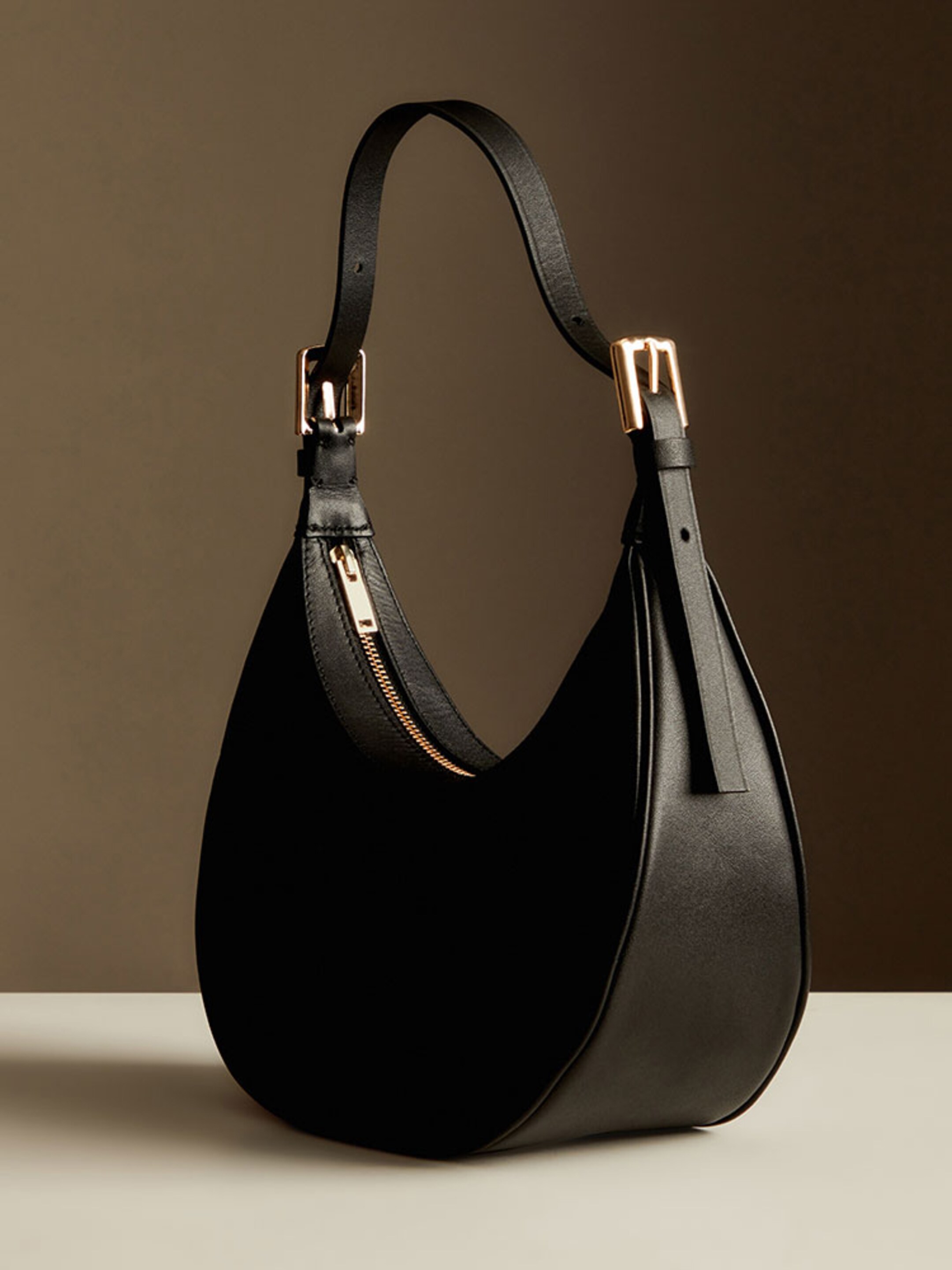 Black curved handbag with gold zip and buckles