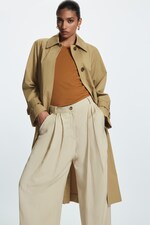 Placeholder for: Woman wearing beige trench, orange top and beige tailored trousers